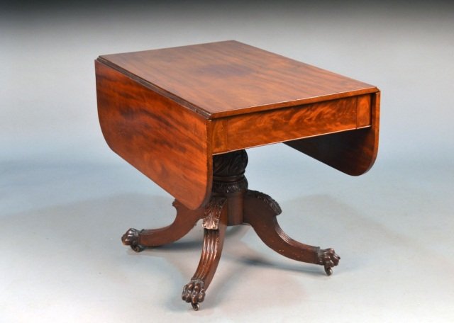 American Empire Style Mahogany Drop Leaf Table: Rectangular top flanked by drop leaves, on a carved standard on four reeded scrolled legs ending in paw feet. Height 29 1/2 inches, width extended 50 inches, depth 38 inches.