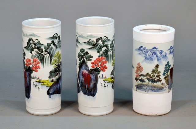 Three Asian Porcelain Umbrella Stands: Comprising a pair of stands with mountain landscapes and another decorated with boats on a lake. Pair, height 24 inches.