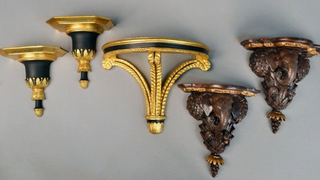 Group of Wall Brackets: Comprising a pair of gilt and ebony decorated neoclassical style brackets, a single neoclassical style bracket, and a pair of carved wood brackets. Single bracket, height 11 inches, width 14 inches.