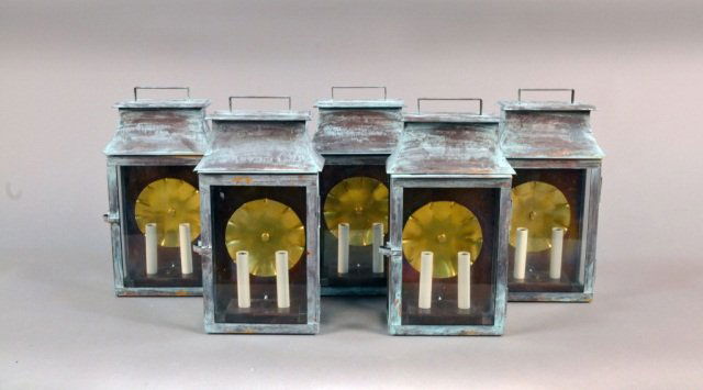 Five Patinated Metal Lantern Sconces: Each a two light candle sconce with glazed panels. Height 16 inches.