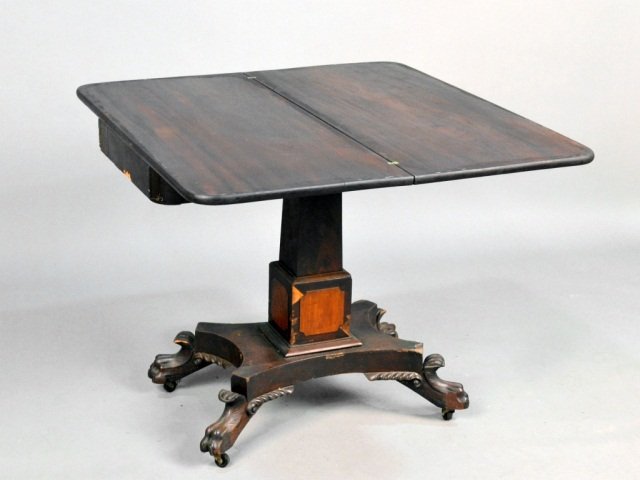 American Empire Mahogany Fold Top Game Table: 19th century, rectangular top with crossbanded edge, on a tapered square pedestal on a quatrepartitie base with paw feet. Height 29 3/4 inches, width 36 inches, depth 17 1/2 inches.