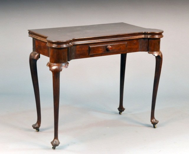 American Mahogany Fold Top Games Table: Massachusetts circa 1760. Rectangular top with outset corners opening to a baize lined interior with cups, above a single false drawer, on turned tapered legs ending in pad feet with brass castors. He