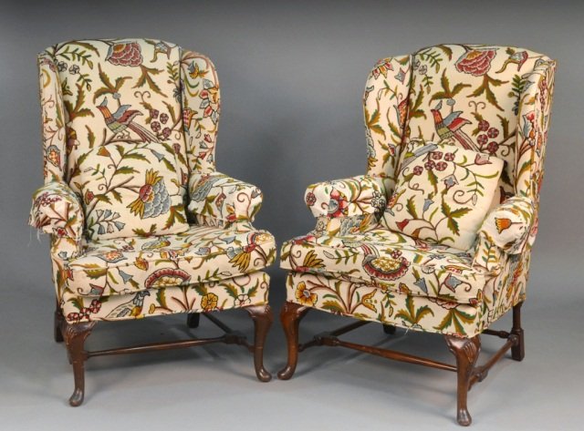 Pair of Queen Anne Style Mahogany Wing Chairs: Floral decorated upholstery, cabriole front legs on pad feet joined by a box stretcher; together with a Louis XV style footstool with matching upholstery. Chairs height 45 inches, width 31 inches, dep