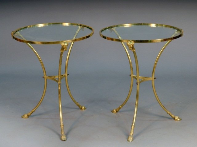 Pair of Glass Top Brass Gueridons: Circular top, ram's head decoration, hoof feet. Height 25 inches, diameter 20 1/2 inches.