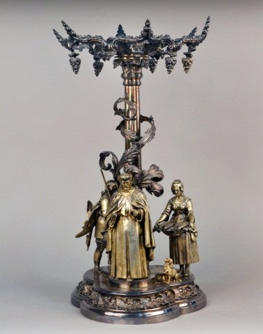 Silver Plated Figural Centerpiece: Trefoil base with three ornate figures. Height 23 1/4 inches.