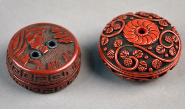 Two Chinese Cinnabar Lidded Boxes: Circular, one with leafy vine decoration, the other with a figure in a garden. Larger, diameter 1 1/2 inches.