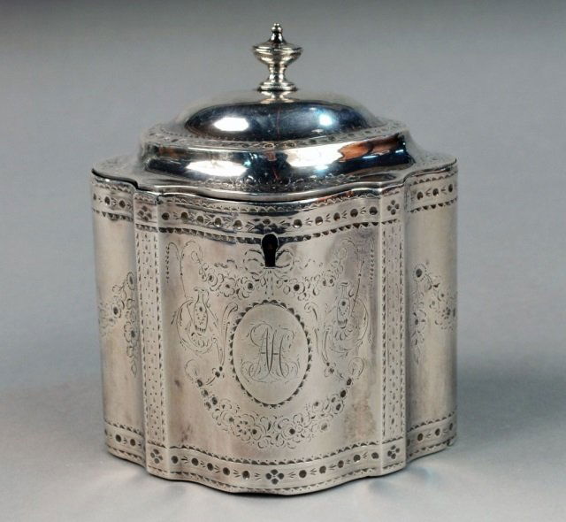 English Silver Tea Caddy: London, 1783, maker's mark of Hester Bateman, Fluted straight-sided oval form, bright-cut engraved with swags, urns and foliage, the front with a coat-of-arms and a monogram, the cover with urn form f
