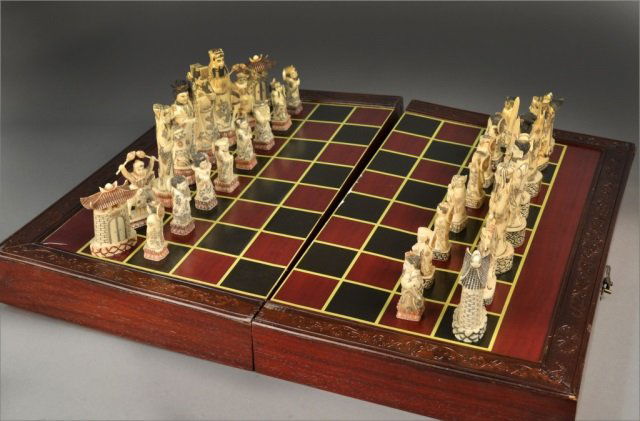 Asian Carved Simulated Ivory Chess Set: Pieces carved wearing traditional ancient dress, in fitted chessboard case. Tallest piece 5 1/2 inches, open board dimensions height 2 1/2 inches, width 24 1/2 inches, depth 21 inches.