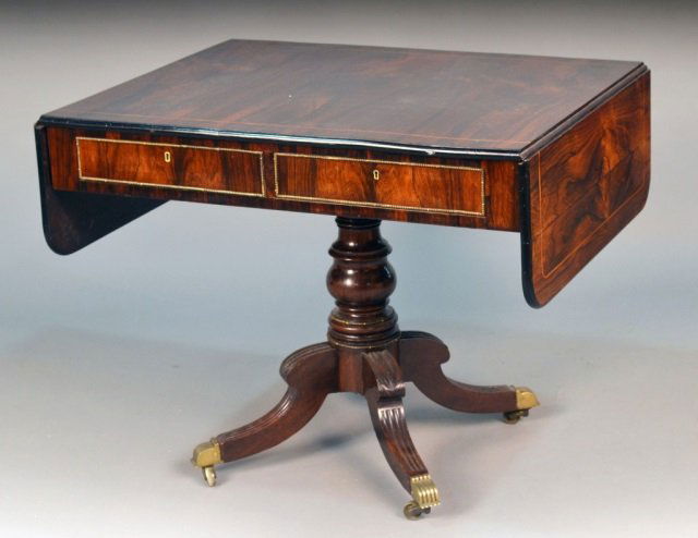 Regency Rosewood Pedestal Sofa Table: Circa 1820, rectangular top with line inlay flanked by two drop leaves over two short drawers with brass beading on a turned support with four fluted scroll legs ending in brass castors. Height 28 1/2