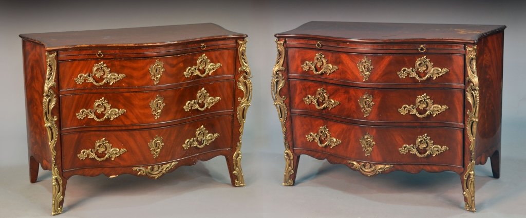Pair of Ralph Lauren Louis XV Style Commodes: Each a mahogany commode with serpentine fronted top over a brushing slide and three drawers, flanked by gilt metal scroll mounts. Height 34 inches, width 46 inches, depth 22 inches.