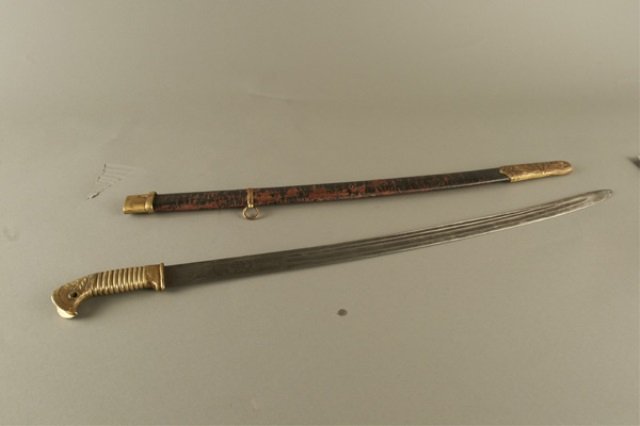 Russian Imperial Shaska Sword *: The triple fuller single edged blade with imperial two headed eagle on one side of the ricasso and a H with a crown and the roman numeral II on the reverse, the bronze handle with an enamel order of S