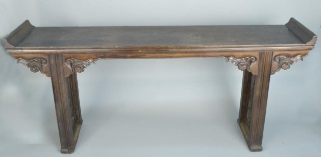 Asian Hardwood Altar Table: Rectangular top with scrolled ends, trestle style base with carved stylized leaf and scroll decoration. Height 35 1/2 inches, width 6 feet 6 inches, depth 15 3/4 inches.