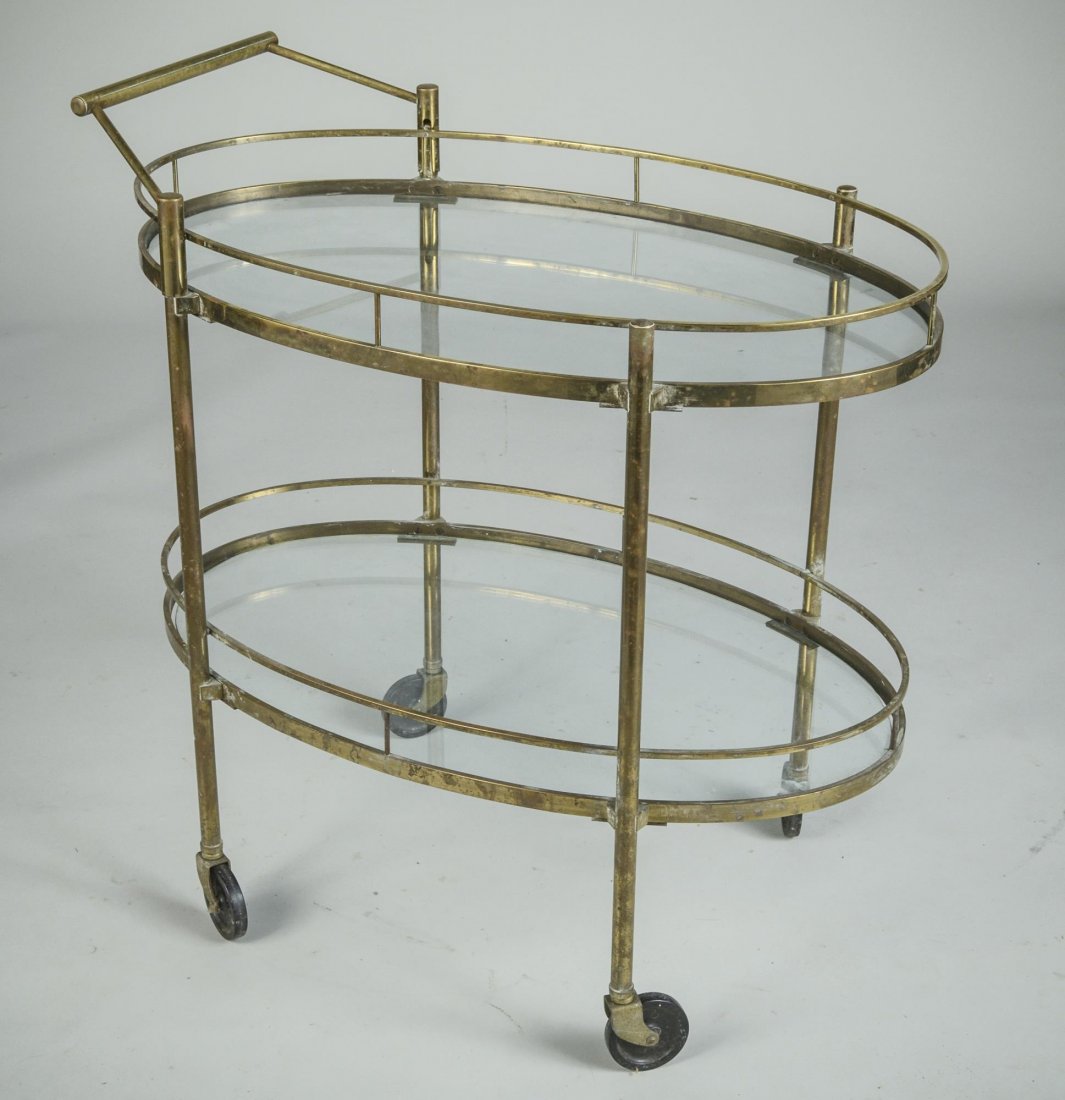 Brass Tea Cart: Two oval glass shelves. Height 31 1/4 inches, width 30 1/2 inches, depth 18 1/2 inches. Provenance: From a Riverdale Estate