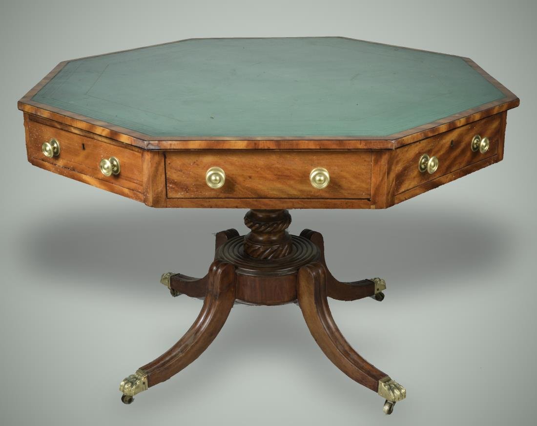Regency Mahogany Drum Table: Green Leather inset octagonal top over drawers, pedestal base with a turned center support on fluted scrolled legs ending in brass paw feet. Height 30 inches, width 44 1/2 inches, depth 44 1/2 inches.
