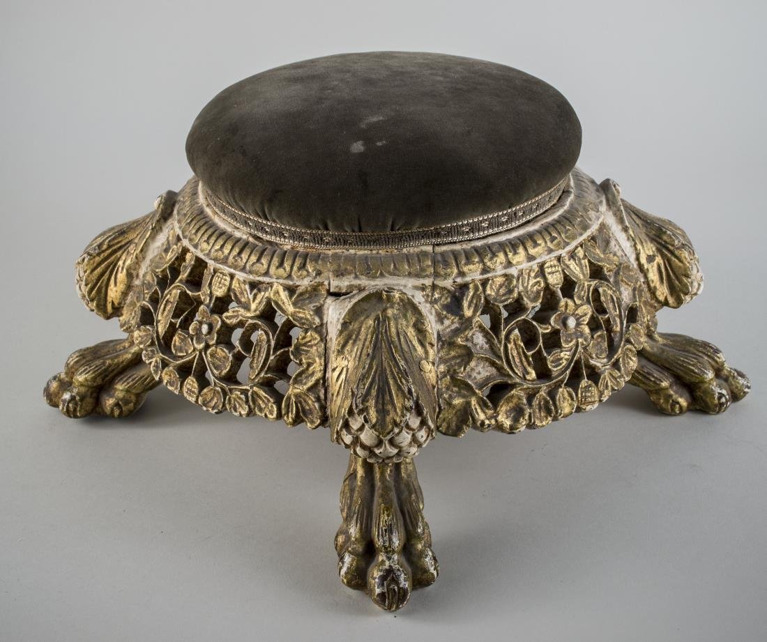Gilt Wood Footstool: Circular upholstered top over a openwork floral carved apron, animal paw feet. Height 10 inches, diameter 16 inches.