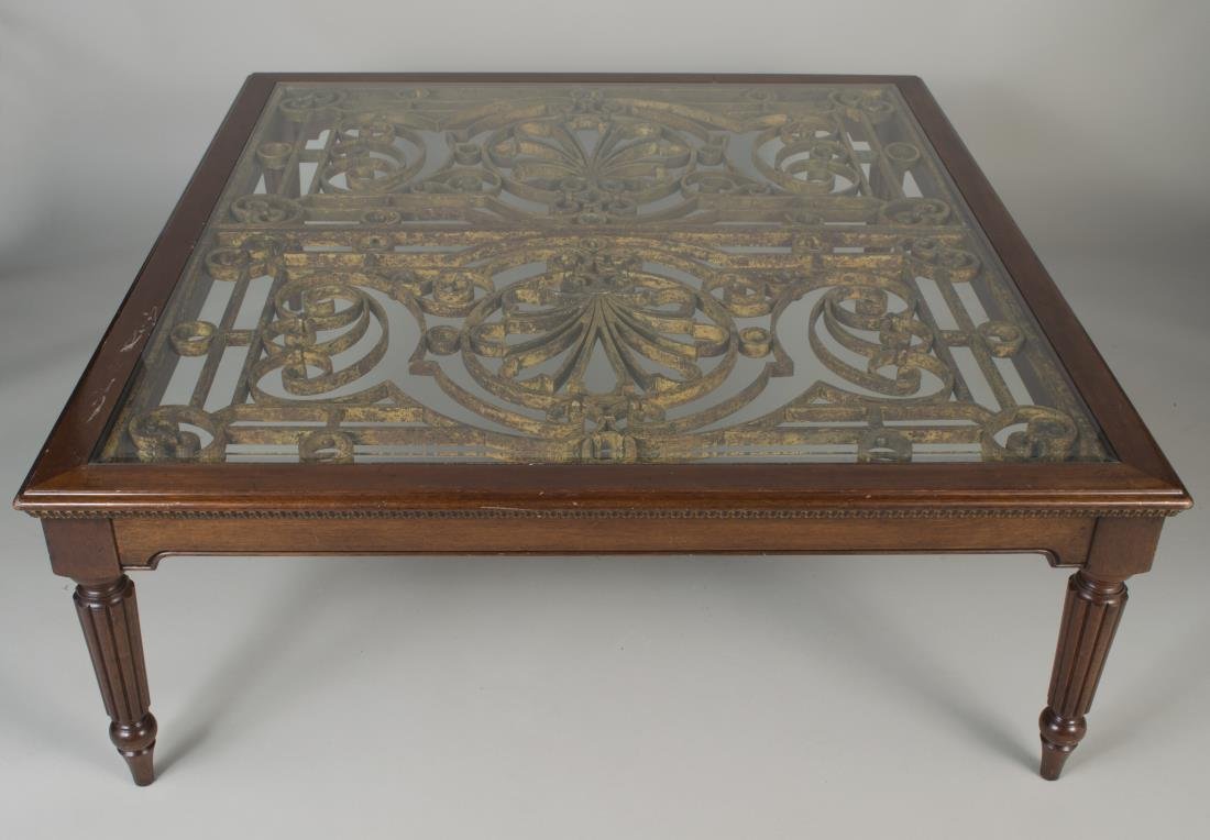Mahogany Glass Top Coffee Table: Rectangular top with gold painted iron gate inset under glass top and molded edge, on tapered reeded legs. Height 18 inches, width 50 1/2 inches, depth 46 1/2 inches.