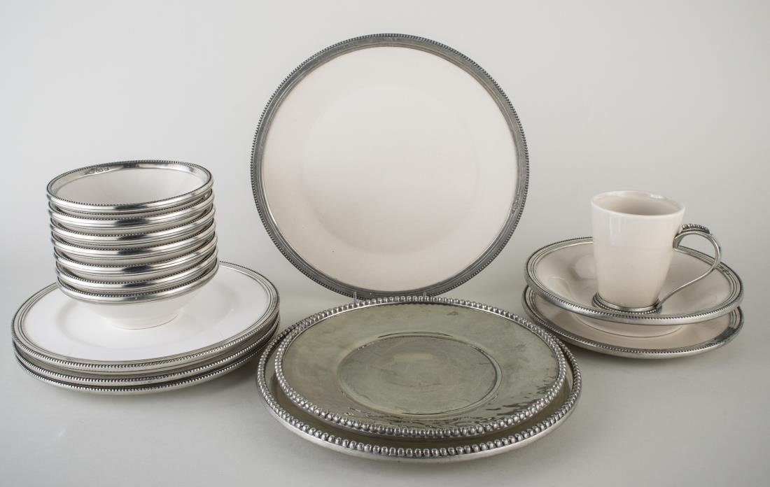 Group of Arte Italica Metal Mounted Dinnerware: Approximately sixteen pieces, both porcelain and glass examples, comprising two chargers, four dinner plates, one salad plate, seven bowls, one mug, and one serving bowl. Dinner plate diameter 11 1/8 