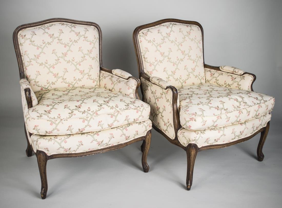 Pair of Louis XV Style Walnut Bergeres: Cartouche shaped back, white floral upholstery. Height 35 inches, width 28 inches, depth 30 inches.