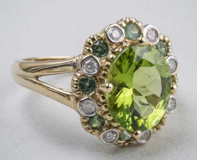 Peridot Ring: 14k yellow gold ring with a central oval faceted peridot within a border of tsavorite garnets and round diamonds. Size 7, 1.8 dwt.