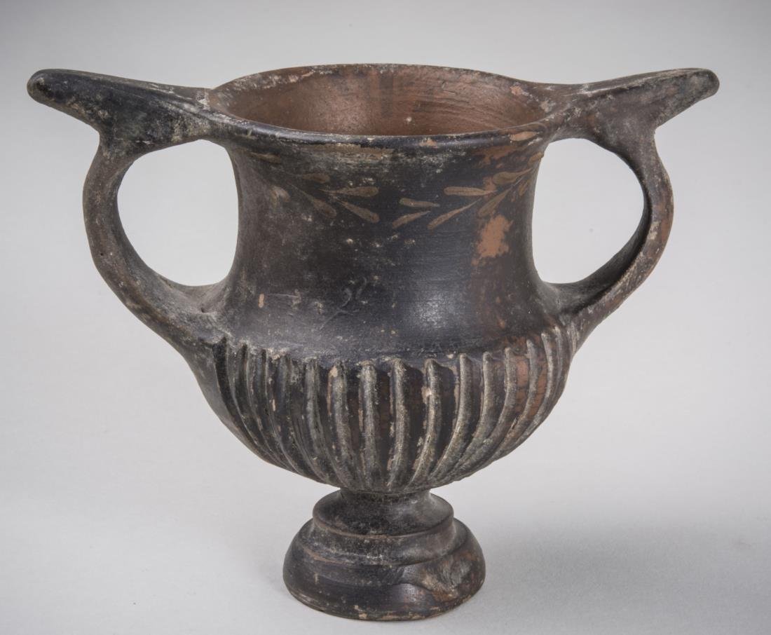 Greek Two handled vessel: Amphora shape with Echinus foot with black matte glaze. Height 3 7/8 inches.