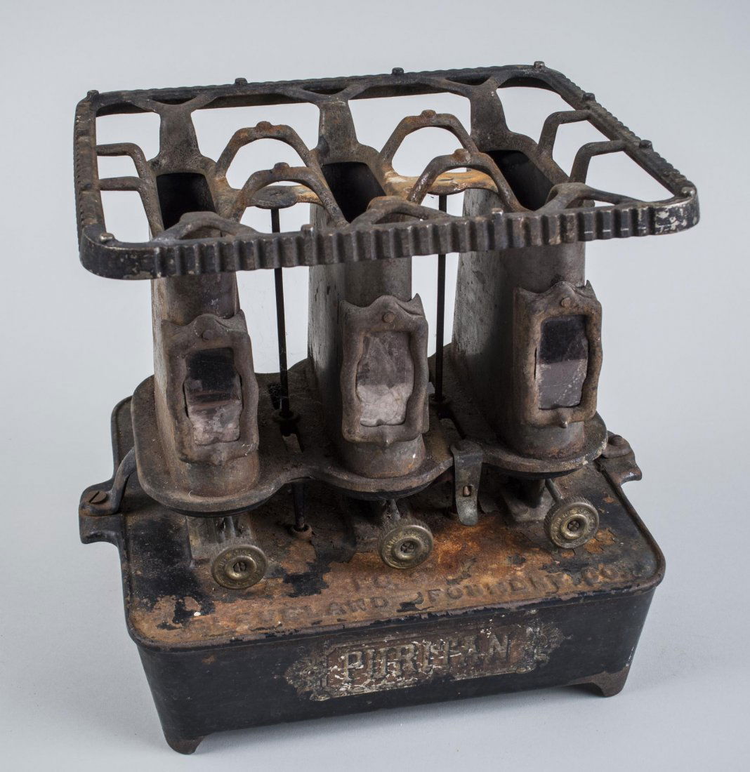 Cast Iron Oil Burning Flat Iron Heater: 1895, by the Cleveland Foundry Co., bearing label for puritan heating oil. Height 10 1/4 inches.