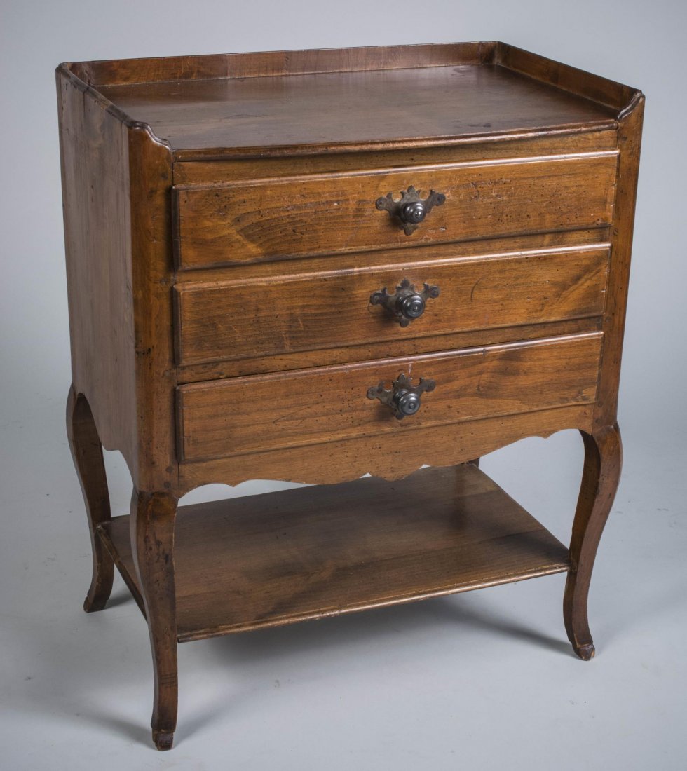 Provincial Fruitwood Commode: Shaped rectangular top with three quarter gallery over three drawers, on slightly cabriole legs joined by a shelf, on hoof feet. Height 29 inches, width 24 inches, depth 16 inches.