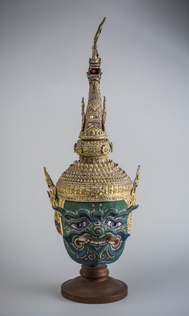 Thai Khon Mask: Green painted face with mother of pearl inlay and polychrome decoration, the gilt dragon form headdress with mirrored tile inlay decoration. Height 27 1/2 inches.