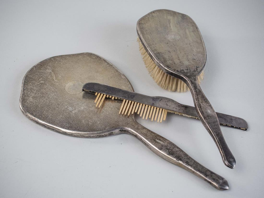 Chinese Silver Three Pieces Dresser Set: Marked Made in Hong Kong, comprising a hair brush, hand mirror and comb. Notice to bidders: Condition reports and additional photographs are provided by request as a courtesy to our clients, as such a