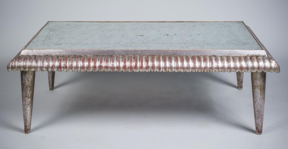 Newcomb Macklin Coffee Table: Rectangular mirrored top with gadrooned edge on a silvered wood base. Height 19 inches, width 49 inches, depth 25 inches. Notice to bidders: Condition reports and additional photographs are provided b