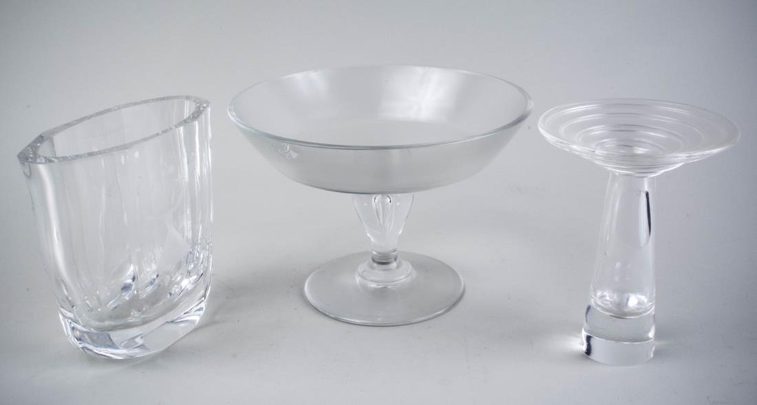 Three Glass Table Decorations: A Steuben candlestick and an Orrefors vase with etched decoration; together with a compote, all signed. Steuben candlestick, height 6 1/4 inches. Notice to bidders: Condition reports and additional ph