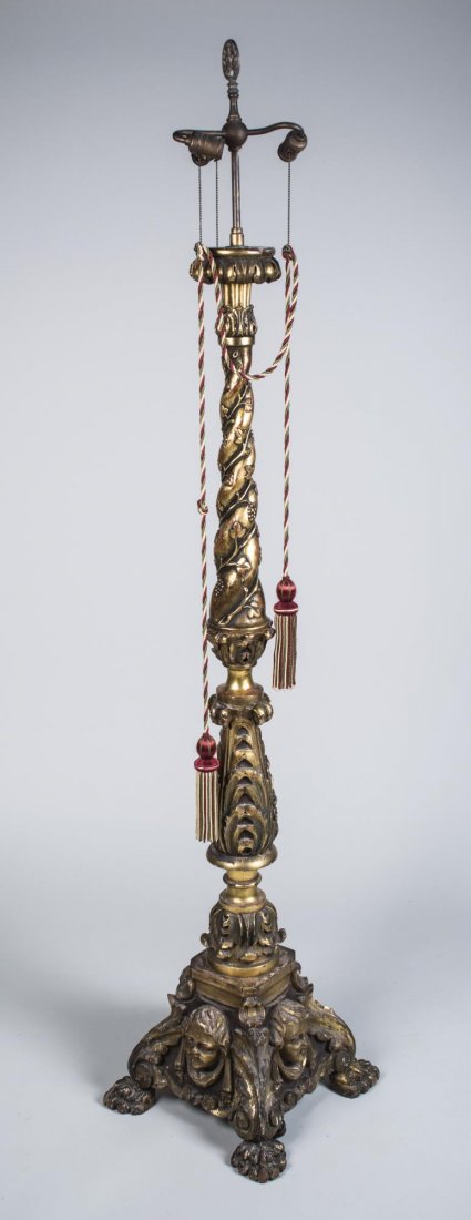 Italian Gilt Wood Altar Stick Lamp: Two light lamp on a tapered support carved with fruit and vine decoration, shaped square base with carved masks, paw feet. Height 6 feet 3 inches. Notice to bidders: Condition reports and additional p