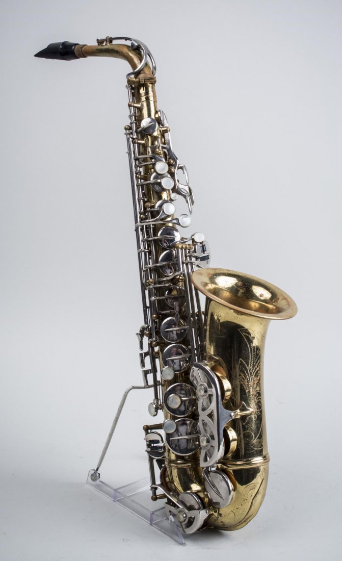 Saxophone: Stamped Capitol and with the serial number 13621 with etched floral and scroll decoration. Height 27 1/2 inches. Notice to bidders: Condition reports and additional photographs are provided by request