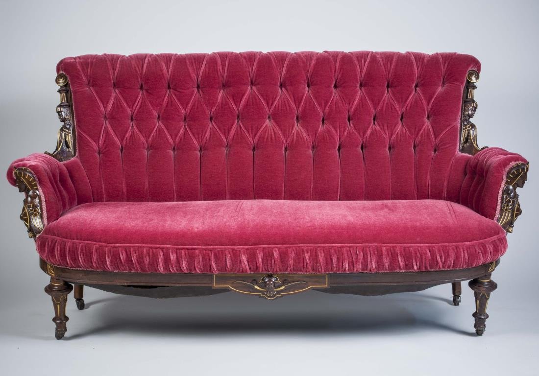 Egyptian Revival Walnut Settee: Button tufted back, flanked by carved parcel gilt Egyptian motif cushion seat, turned legs. Height 38 inches, width 6 feet 1 inch, depth 35 inches. Notice to bidders: Condition reports and additional 