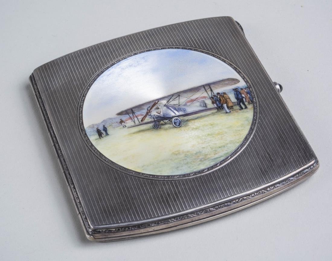 Silver and Enamel Cigarette Case: Engine turned decoration with a central enamel picture of a biplane. 3 1/4 x 3 1/2 inches. 120 grams. Notice to bidders: Condition reports and additional photographs are provided by request as a court