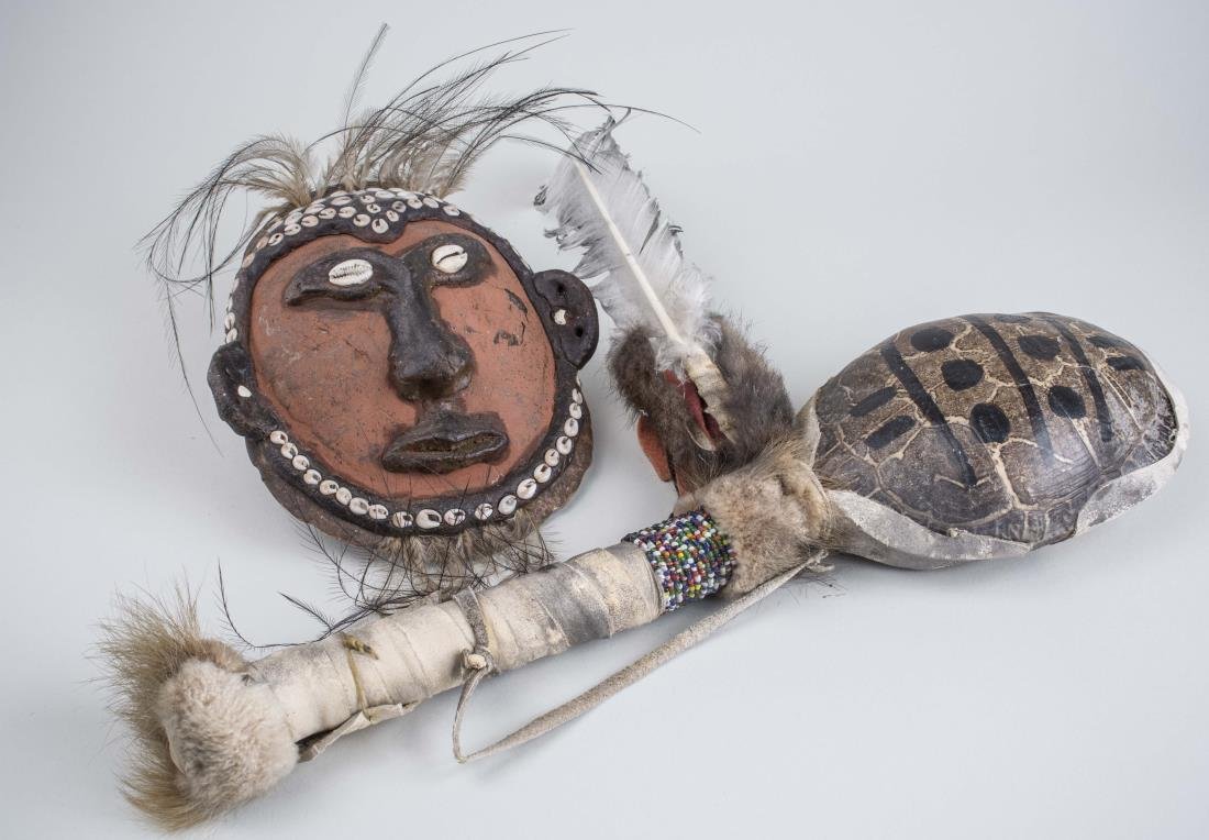 Two Turtle Shell Articles: Including a rattle and a mask, each with polychrome decoration, and shell, leather, fur or feather accents. Rattle length 17 inches. Notice to bidders: Condition reports and additional photographs are