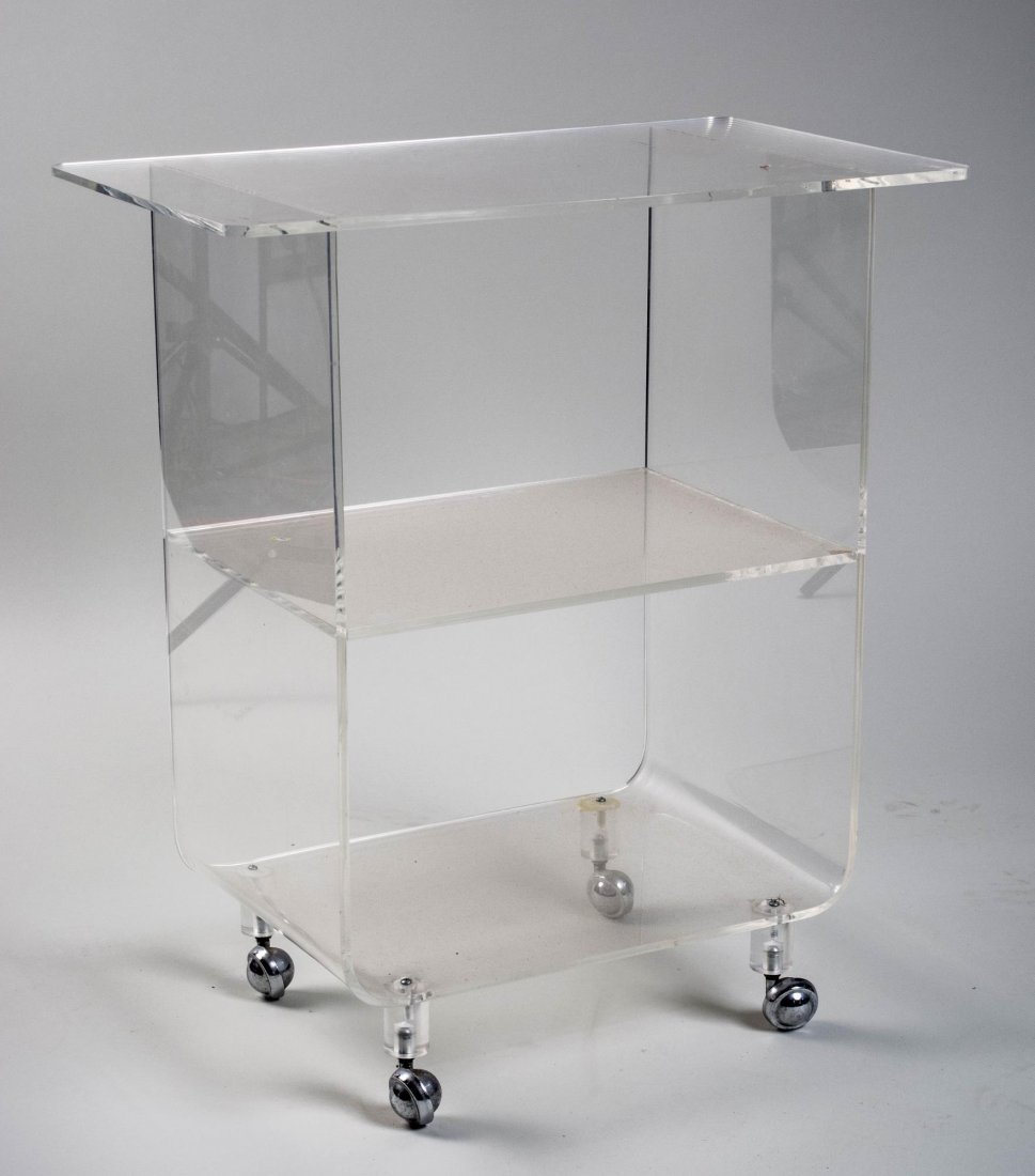Lucite Tea Cart: Rectangular top with rounded corners, over a medial and lower shelf, on chromed metal casters. Height 30 inches, width 27 inches, depth 16 inches. Notice to bidders: Condition reports and additional p