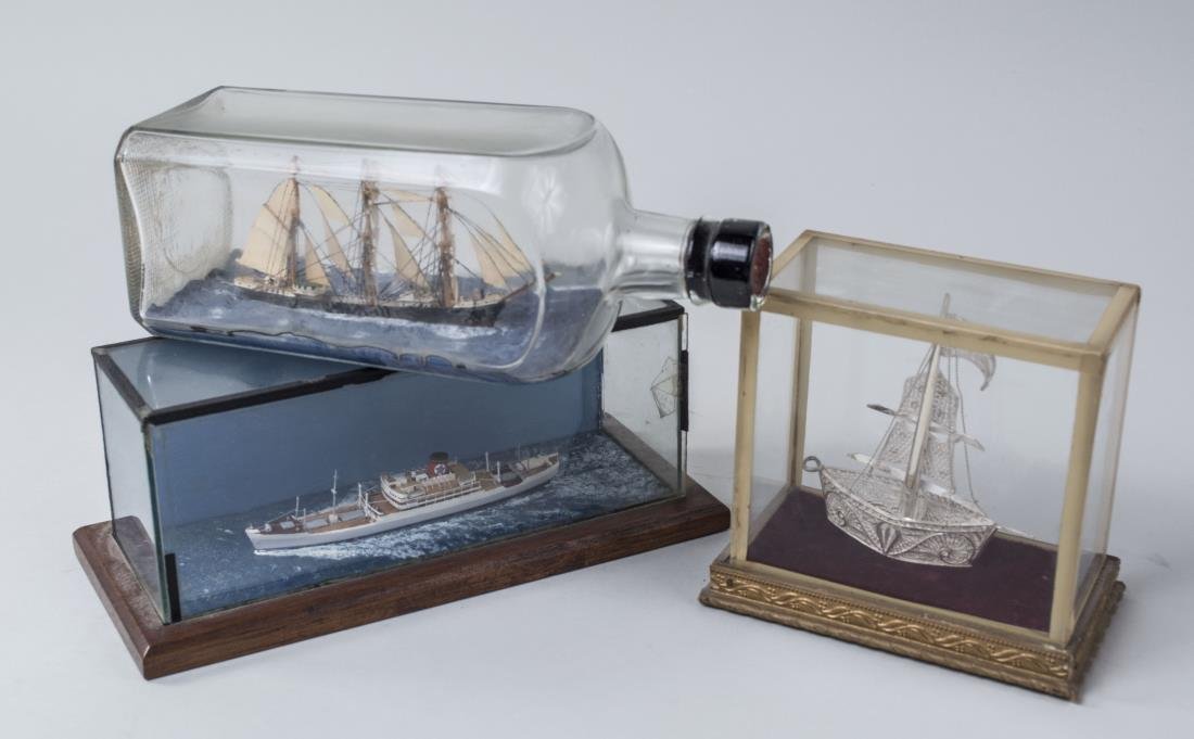 Three Ship Models: One in glass bottle, two in glass cases. Tallest height 4 7/8 inches. Notice to bidders: Condition reports and additional photographs are provided by request as a courtesy to our clients, as such any