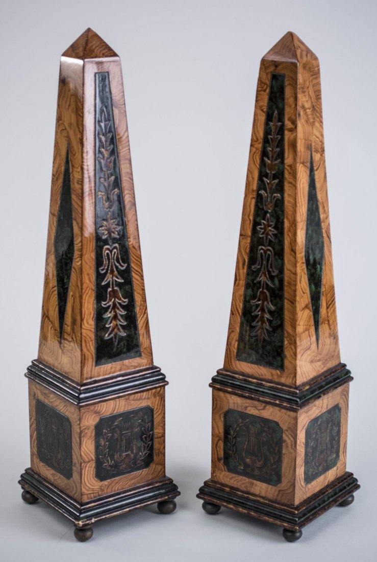Pair of Grain Painted Obelisks: Neoclassical style, faux wood obelisks with bell flower and lyre decoration, bun feet. Height 18 1/2 inches. Notice to bidders: Condition reports and additional photographs are provided by request as