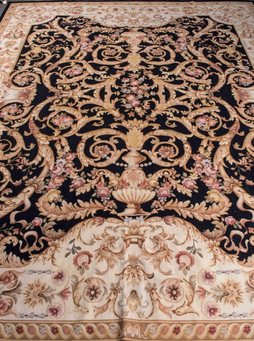 Needlepoint Carpet: Neoclassical style urn and leafy scroll pattern on a black field, within a cream border. 9 feet 10 inches x 7 feet 10 inches Notice to bidders: Condition reports and additional photographs are provide