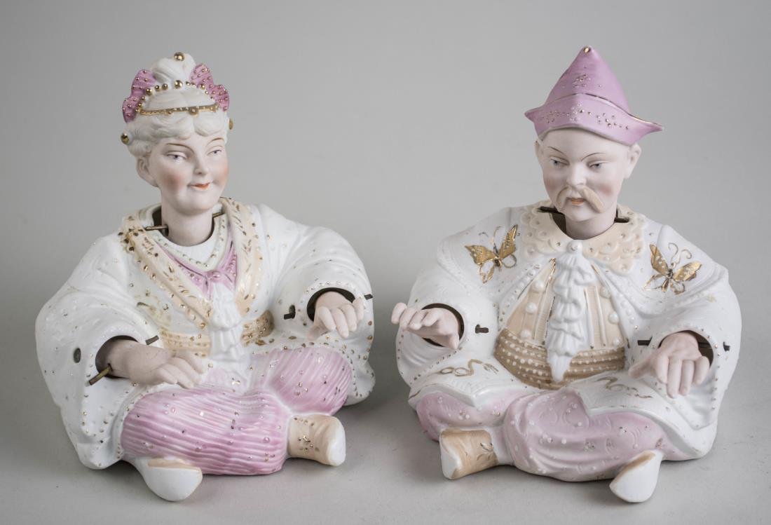 Pair of Porcelain Nodder Figures: Depicting an orientalist man and woman, seated with nodding heads and hands. Height 5 inches. Notice to bidders: Condition reports and additional photographs are provided by request as a courtesy to o