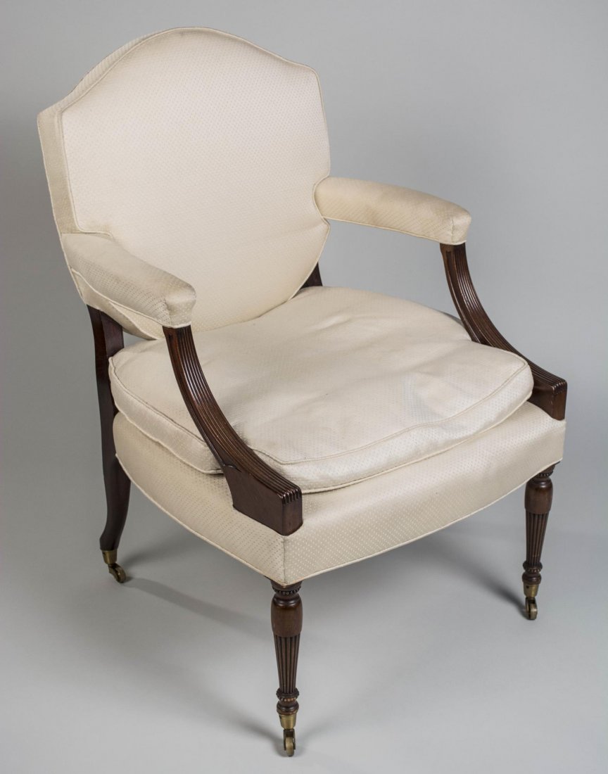 George Smith Armchair: In the style of William IV, upholstered shield back, padded arms, cushion seat, inverted baluster turned legs ending in brass casters. Height 39 inches, width 27 inches, depth 29 inches. Notice to bid