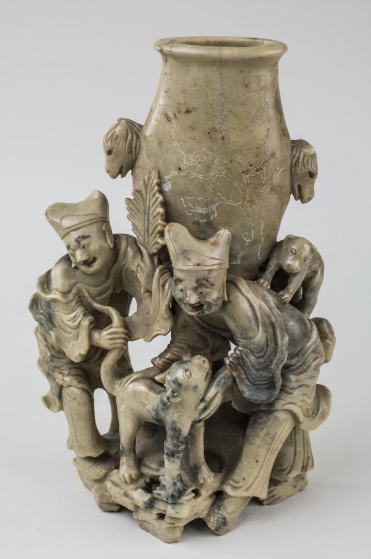 Chinese Carved Soapstone Figural Vase: 19th Century, the swelling vase flanked by animal mask handles, the base with two figures and a dog. Height 12 1/2 inches. Notice to bidders: Condition reports and additional photographs are provided 