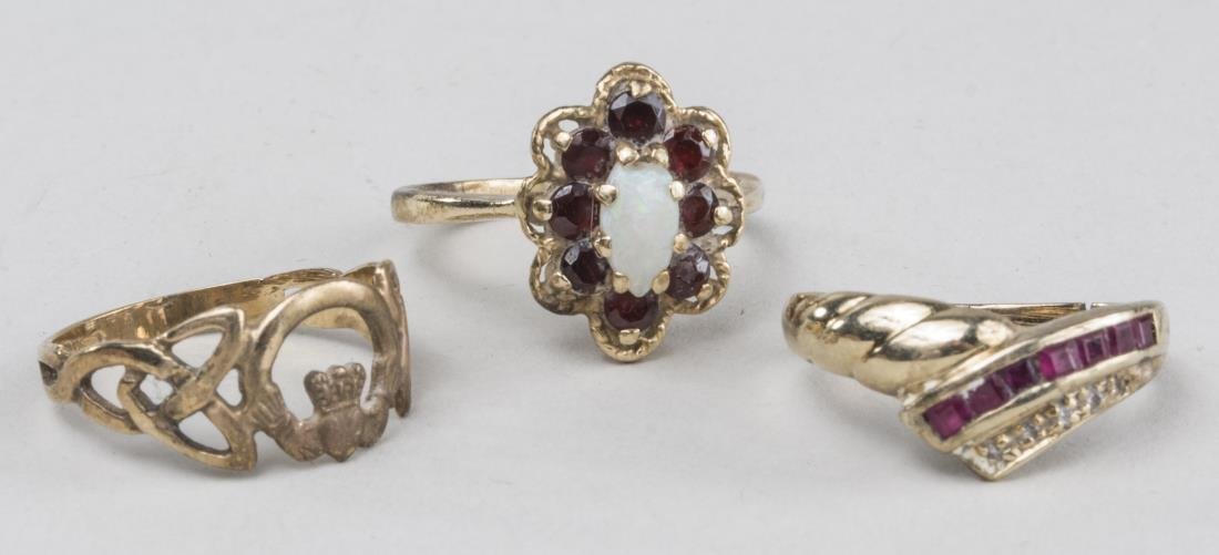 Three Gold Rings: Two14k yellow gold rings one with opal and garnets and the other with diamonds and calibre rubies; together with a 10k yellow gold band. Total7.4 grams. Notice to bidders: Condition reports and additi
