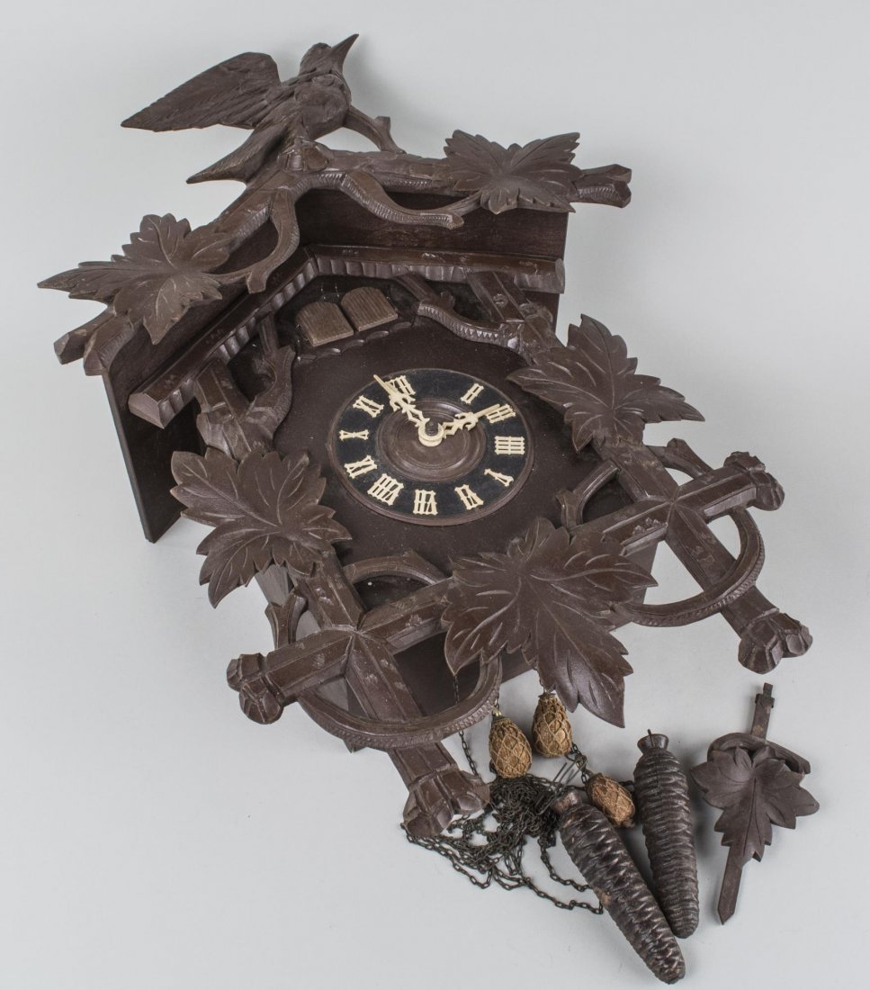 Black Forest Cuckoo Clock: Decorated with oak leaves and surmounted by a bird, two train movment. Height 19 inches. Notice to bidders: Condition reports and additional photographs are provided by request as a courtesy to our cl