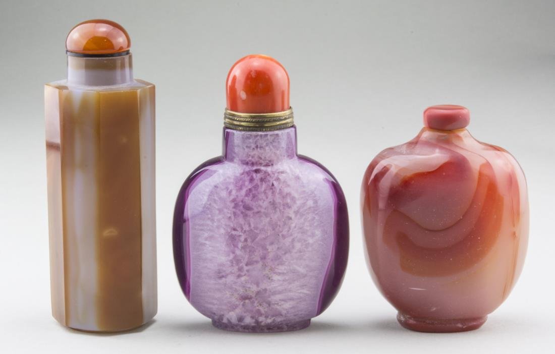 Three Chinese Snuff Bottles: Comprising one carved hardstone, one carved carnelian, and one glass bottle. Tallest height 2 5/8 inches. Provenance: From the Collection of Erwin A. Raible Notice to bidders: Condition reports and ad