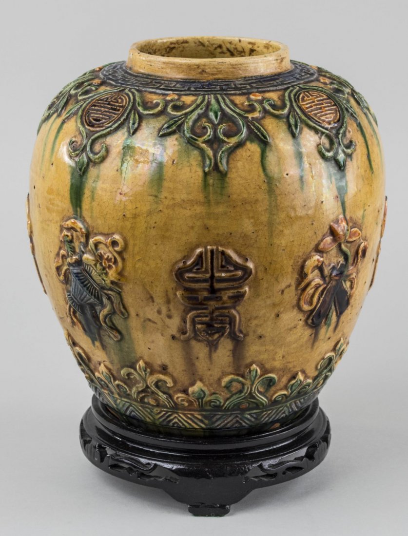 Chinese Ceramic Vase: Ovoid, with Sancai glazed with Asian character decoration at the shoulders, height 10 inches, with a carved wood stand. Notice to bidders: Condition reports and additional photographs are provided by 