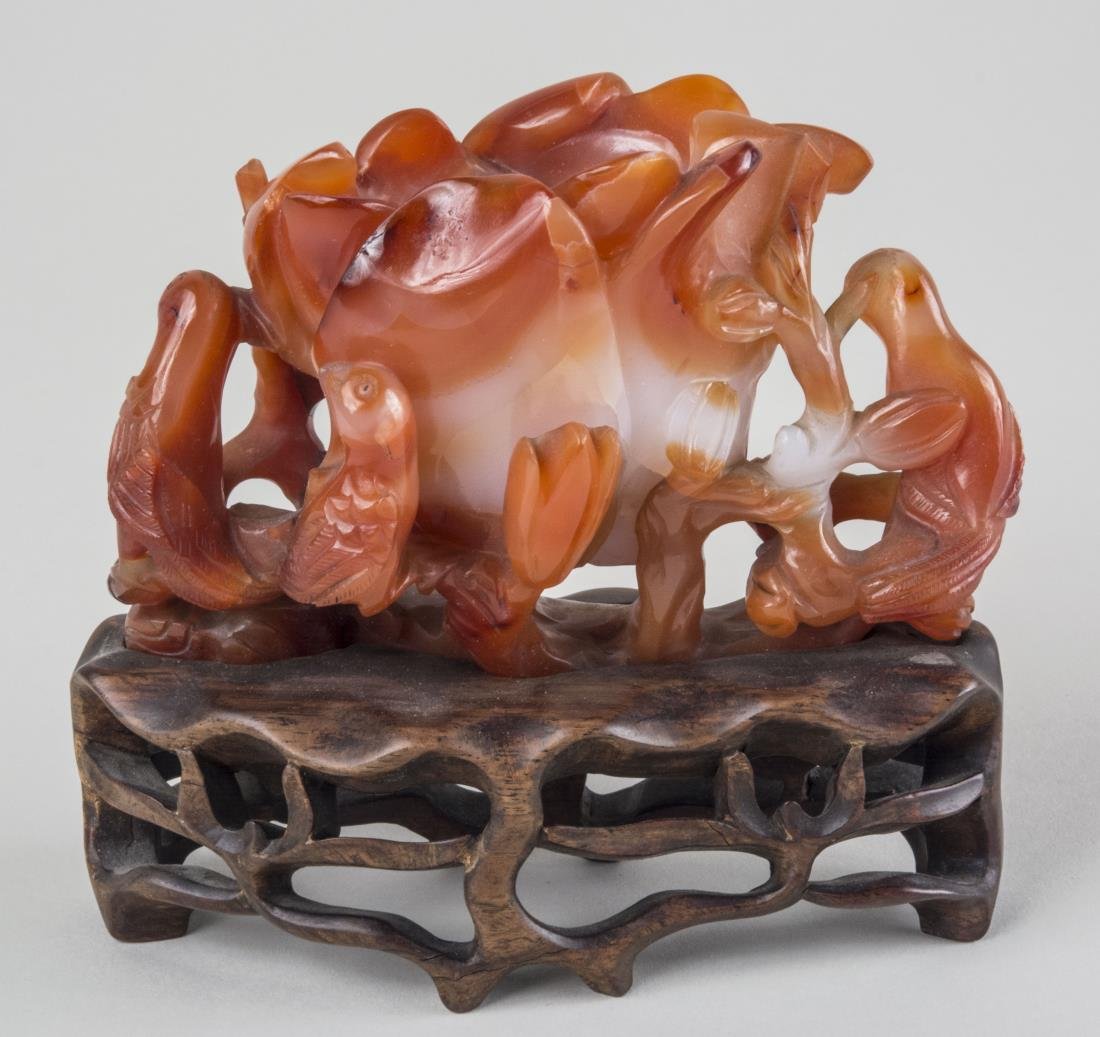 Chinese Carved Carnelian Vase: Flower form vase, height 3 1/2 inches, length 5 inches, on a carved hardwood stand. Notice to bidders: Condition reports and additional photographs are provided by request as a courtesy to our clients