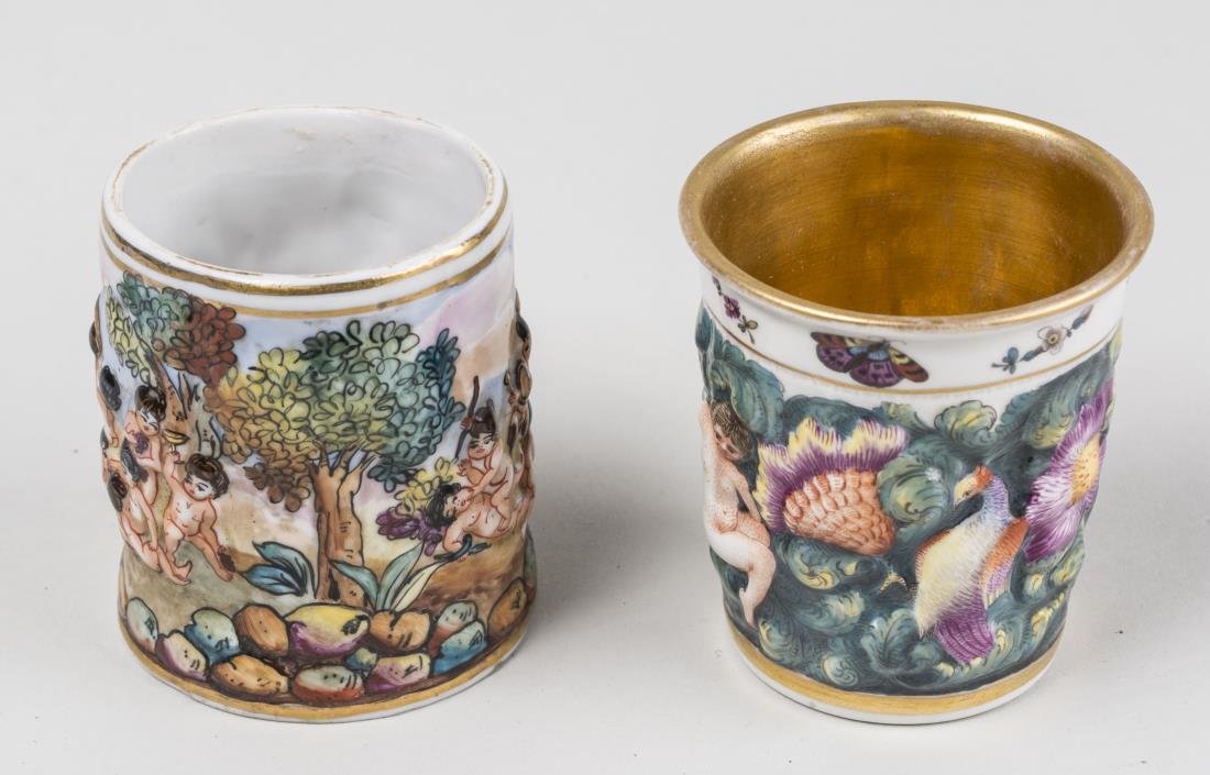 Two Capo di Porcelain Beakers: Both wirh raised decoration of putti. Height 3 1/4 inches, diameter 2 1/2 inches. Provenance: From the Collection of Erwin A. Raible Notice to bidders: Condition reports and additional photographs are