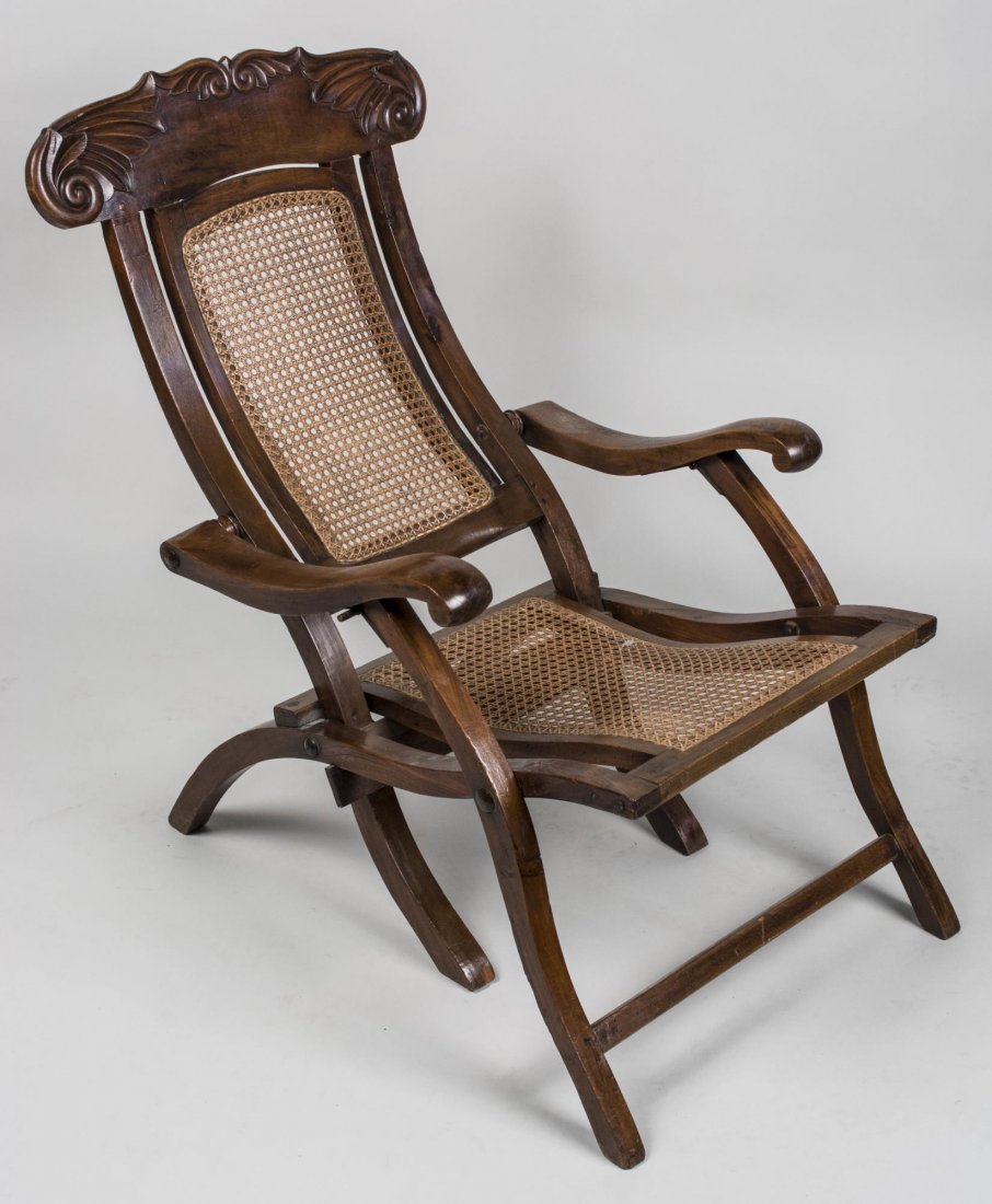 Caned Seat Chaise Longue: With a carved crest rail, down scrolled arms, caned back and seat. Height 36 inches, width 24 inches, depth 34 inches. Notice to bidders: Condition reports and additional photographs are provided by r