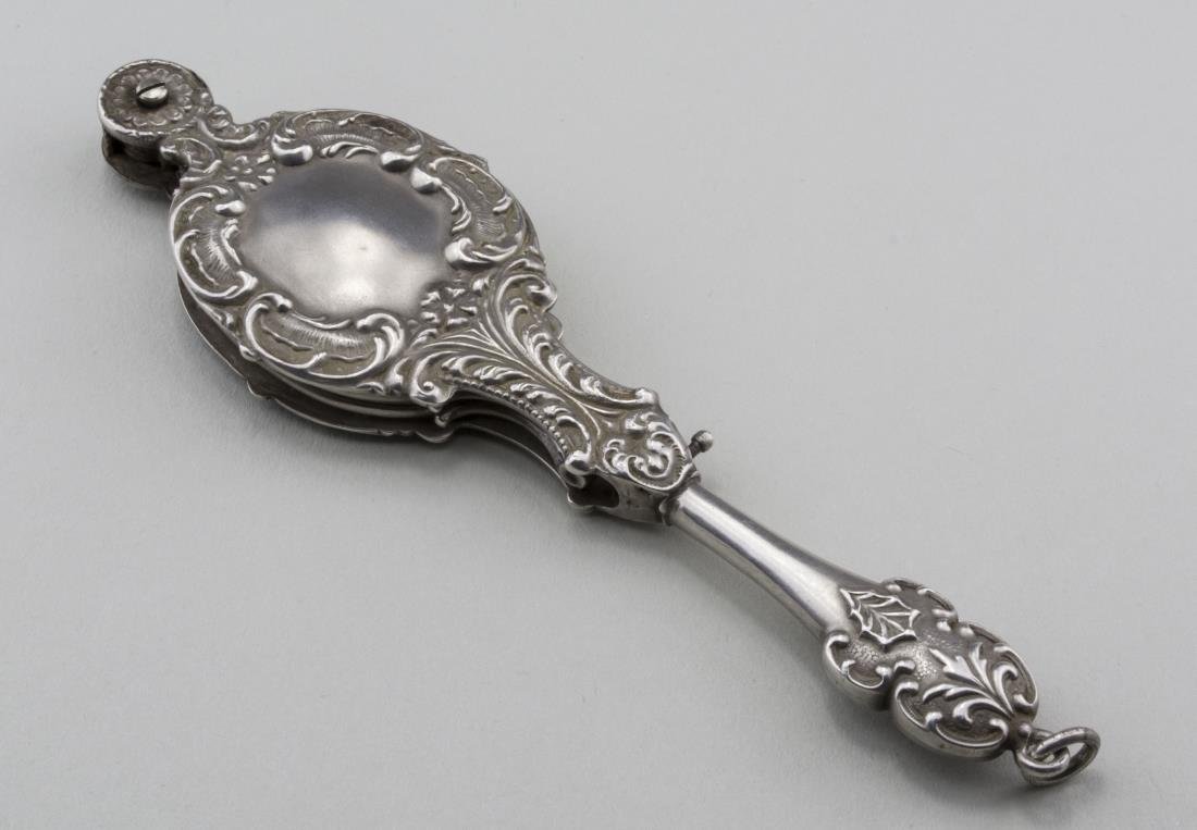Lorgnette: Early 20th century, silvertone brushed metal case with floral and scroll decoration, enclosing a pair of folding glasses. Length, closed, 4 3/4 inches. Notice to bidders: Condition reports and additio